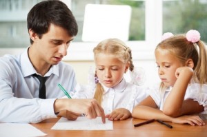 Teacher helping elementary school pupils with their tasks